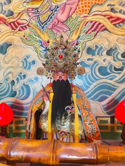 文昌帝君神像：頭戴珠冠、長鬚，身披繡袍端坐，身後為海浪彩繪