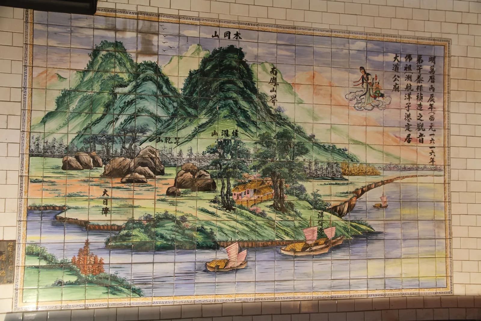 廟內磁磚壁畫：青綠山巒與港灣，水邊停泊數艘帆船，右上雲端繪觀音佛祖，題字起首為「明萬曆丙辰年」（攝於 2015 年）